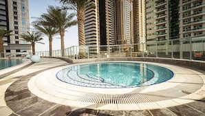 A circular pool with a tiled edge, surrounded by palm trees and tall buildings.