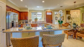 A spacious kitchen with wooden cabinets, a large island with seating, and a dining area with a chandelier.