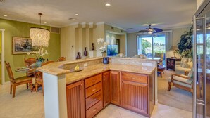 A spacious kitchen with wooden cabinets, a granite countertop, and a dining area with chairs and a table.