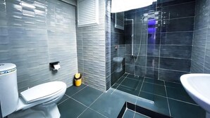 A modern bathroom with a toilet, sink, and shower area. - De La Elpida Otel (Izmir)