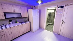 A kitchen with wooden cabinets, a built-in microwave, a refrigerator, and a gas stove. - De La Elpida Otel (Izmir)