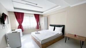 A modern bedroom with a bed, a desk, a wardrobe, and a television. - De La Elpida Otel (Izmir)