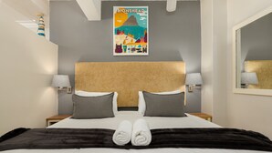 Una camera d'hotel con un letto, due abat-jour, una testiera e uno specchio a parete.