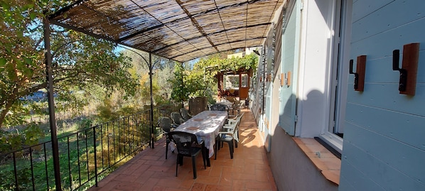 An outdoor patio with a covered seating area, a table, and chairs.
