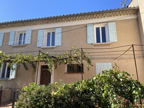 A building with a tiled roof, multiple windows with shutters, and a door.