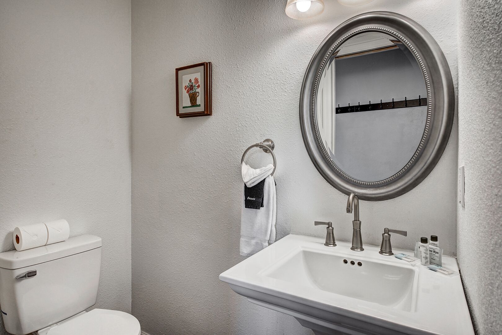 A bathroom with a toilet, sink, and mirror.