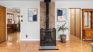 Un salon moderne doté d’un poêle à bois, d’un plancher en bois et d’œuvres d’art abstraites accrochées aux murs.