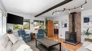 Un salon comprenant un canapé, des fauteuils, une table basse, une cheminée et un téléviseur.