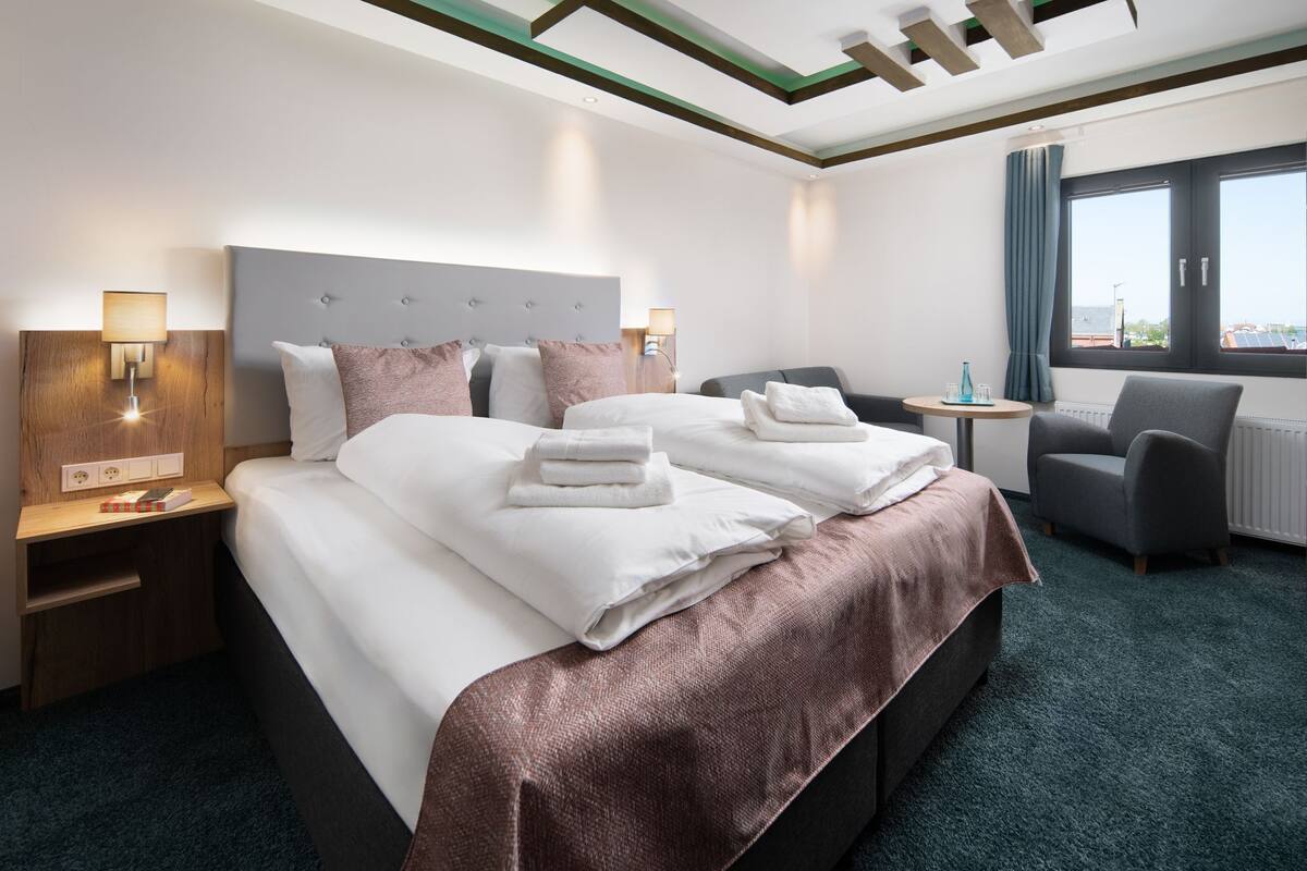 Ein Hotelzimmer mit zwei Betten, einem Schreibtisch, einem Stuhl und einem Fenster mit Blick.