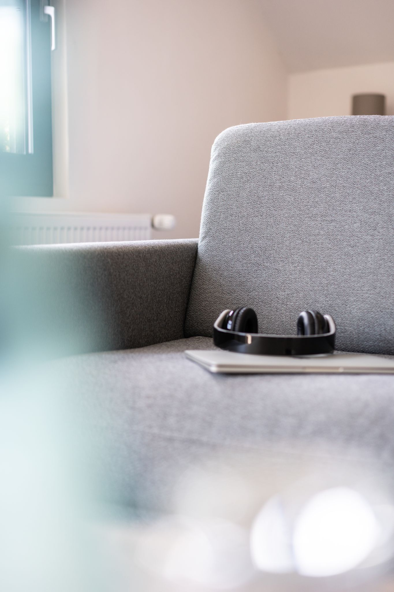 A grey sofa with a pair of black headphones on it.