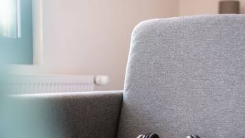 A grey sofa with a pair of black headphones on it.