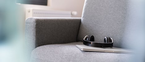 Een grijze bank met een laptop en zwarte koptelefoon.