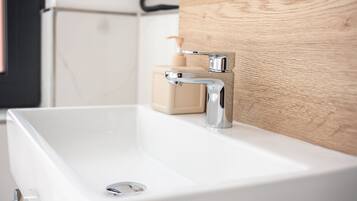 A modern bathroom with a white sink, chrome faucet, and wooden paneling.