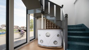 A modern interior with a staircase, a large window, and a Volkswagen-themed decor element. - Nordseehotel Tausendschön (Wittmund)