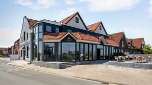 A modern building with large glass windows and a red-tiled roof. - Nordseehotel Tausendschön (Wittmund)