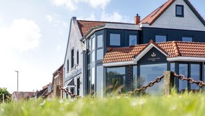 A modern hotel with a mix of traditional and contemporary architecture, featuring large windows and a prominent entrance. - Nordseehotel Tausendschön (Wittmund)