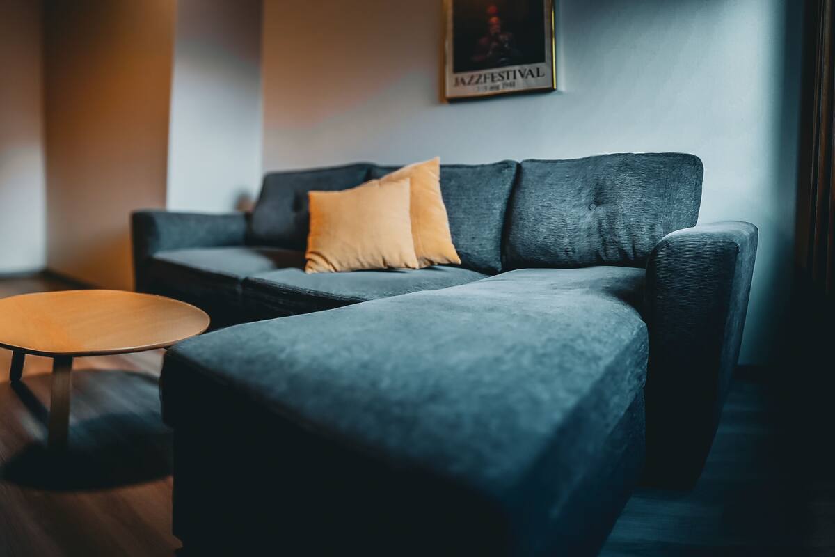 A modern living room with a grey sofa, a round coffee table, and a small dining table with chairs.