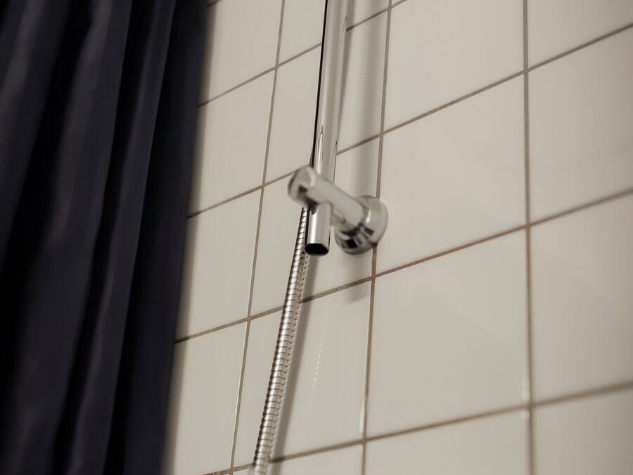 A shower with a handheld showerhead and a wall-mounted faucet.