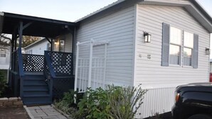 Una casa móvil de un piso con porche cubierto y un pequeño jardín.