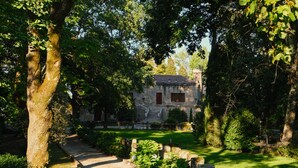 Un edificio in pietra dal design tradizionale, immerso nel verde e con un vialetto in pietra che conduce all'ingresso.