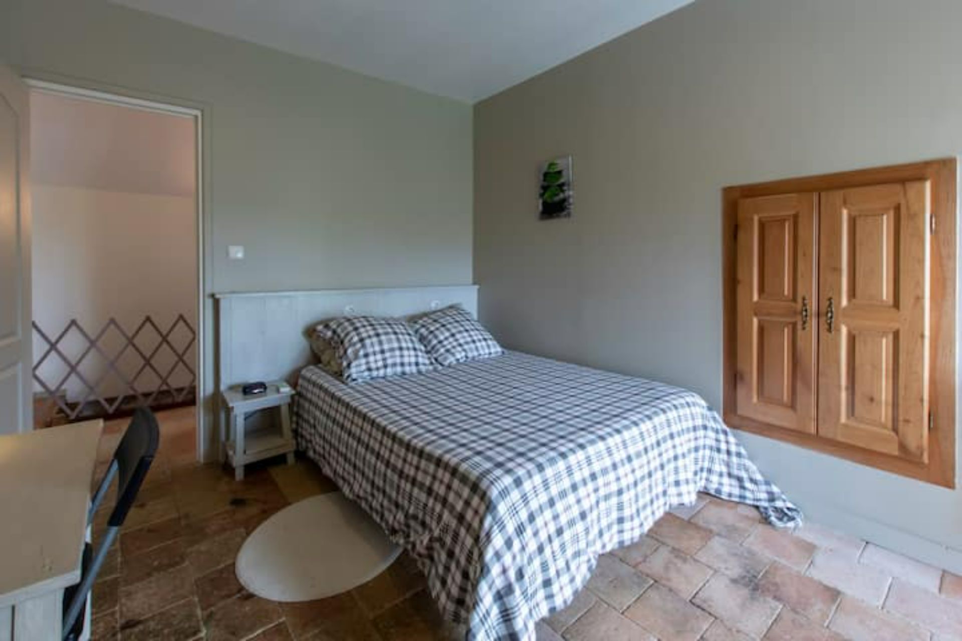 A bedroom with a bed, nightstand, and a wooden wardrobe.