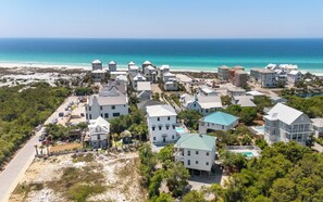 A coastal residential area with houses, a beach, and a clear view of the ocean.