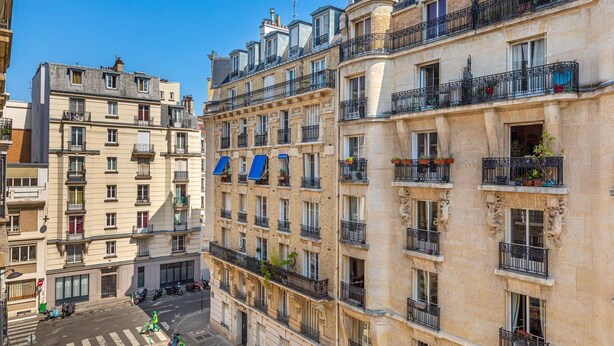 Un edificio de varios pisos con balcones, ventanas y vista a la calle.
