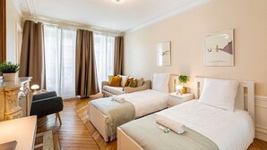Une chambre d’hôtel avec deux lits, un canapé, un bureau et un lustre.