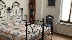 Quarto com cama, estante, radiador e janela.