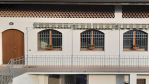 Um edifício com três janelas em arco, cada uma com porta de madeira e uma pequena varanda com grades de metal.