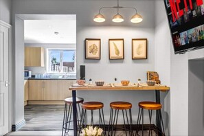 Une cuisine moderne dotée d’un îlot central, de tabourets de bar et d’œuvres d’art encadrées accrochées au mur.