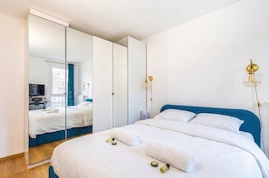 Quarto com cama, espelho e luminária na parede.