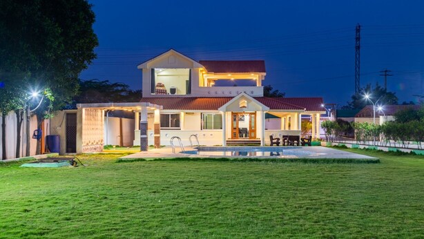 A two-story house with a swimming pool, a covered patio, and a well-maintained lawn. - Bliss Farm Stay-IRIS (Hyderabad)