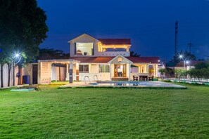 A two-story house with a swimming pool, a covered patio, and a well-maintained lawn. - Bliss Farm Stay-IRIS (Hyderabad)