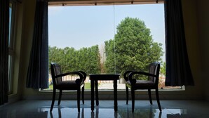 A room with a large window, two chairs, and a table. - Bliss Farm Stay-IRIS (Hyderabad)