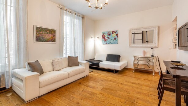 A modern living room with a white sofa, a coffee table, a dining table with chairs, and artwork on the walls. - GuestReady - Minimalist stay near Opéra Bastille (Paris)