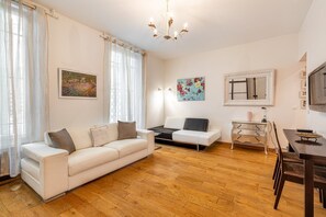 A modern living room with a white sofa, a coffee table, a dining table with chairs, and artwork on the walls. - GuestReady - Minimalist stay near Opéra Bastille (Paris)