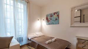 A bedroom with a bed, a bedside table, a chair, a dresser, a painting, and a window with curtains. - GuestReady - Minimalist stay near Opéra Bastille (Paris)