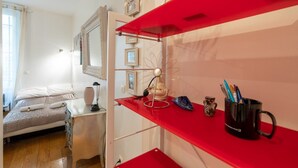 A bedroom with a bed, a desk, and a red shelving unit with decorative items. - GuestReady - Minimalist stay near Opéra Bastille (Paris)