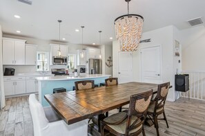 A modern kitchen with white cabinets, a wooden dining table, and a chandelier. - Beautiful house at Lost Key Resort Perdido Key (Perdido Key)