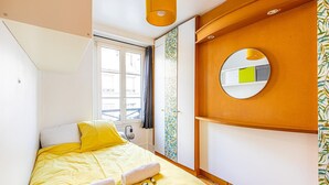 Une chambre à coucher de taille réduite, comprenant un lit, un miroir et une fenêtre.