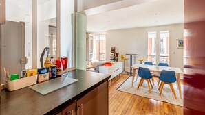 Une cuisine moderne dotée d’un grand îlot central, d’un coin repas avec des chaises bleues et offrant une vue sur l’extérieur.