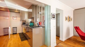 Une cuisine moderne avec un îlot central, une chaise rouge et des tableaux encadrés accrochés au mur.