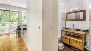 A modern bathroom with a wooden vanity, a glass bowl sink, and a large mirror. - GuestReady - Peaceful Haven in Gare (Paris)