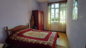 Een slaapkamer met een bed, een kledingkast en een raam met gordijnen.