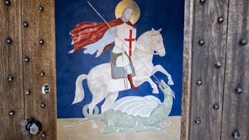 A medieval knight on horseback with a red cape and a white horse, depicted in a painting.