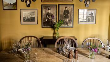 Una mesa de comedor dispuesta con copas de vino, platos y cubiertos, rodeada de sillas.