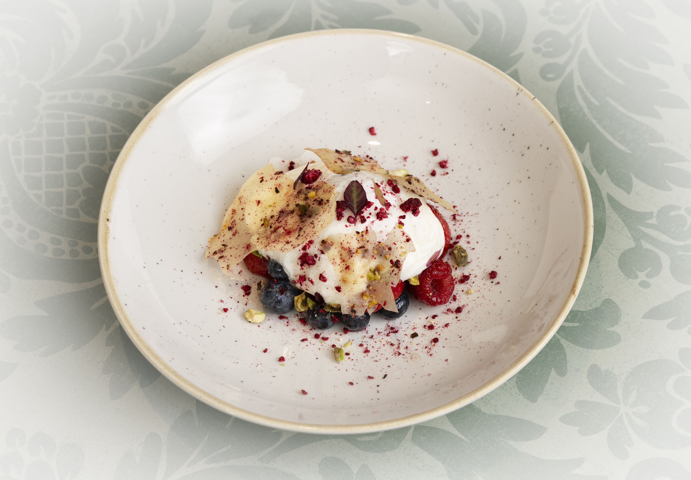 Ein Dessert auf einem Teller mit Beeren und Nüssen.