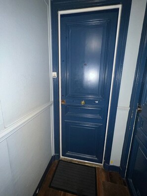 A dark blue door with a brass doorknob and a small window above it.