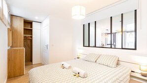 Un dormitorio con una cama grande, un armario, un espejo y una ventana.